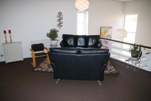 a black leather couch in a living room at Nykøbing Falster Vandrehjem in Nykøbing Falster