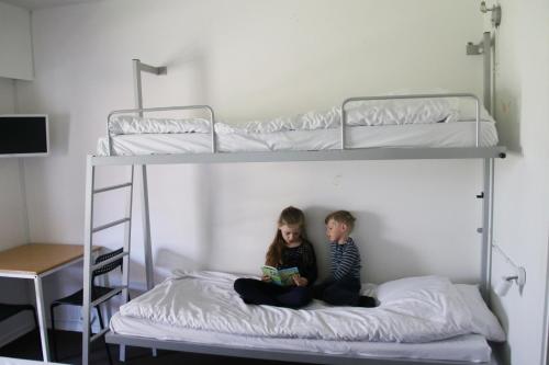 two children sitting on a bunk bed reading a book at Nykøbing Falster Vandrehjem in Nykøbing Falster