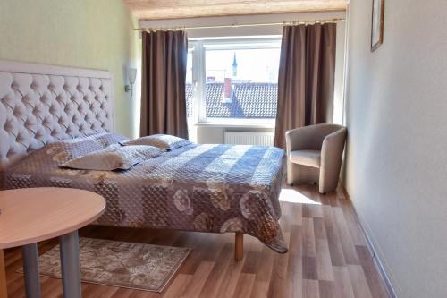 a bedroom with a bed and a table and a window at Aismares in Klaipėda