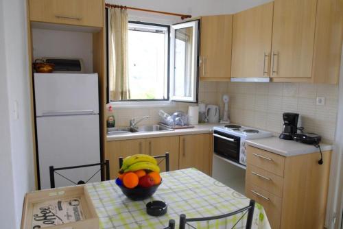 a kitchen with a table with a bowl of fruit on it at Marathona's Apartment in Aegina Town