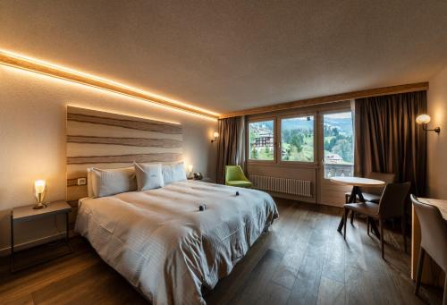 ein Hotelzimmer mit einem großen Bett und einem Fenster in der Unterkunft Hotel Maya Caprice in Wengen