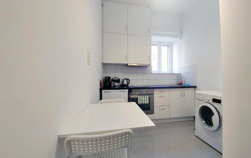 una cucina bianca con tavolo e lavatrice di KYMA Apartments - Athens Acropolis 2 ad Atene