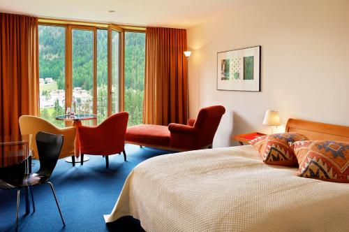 Hotel Saratz Pontresina في بونتريسنا: غرفة فندقية بسرير وطاولة وكراسي