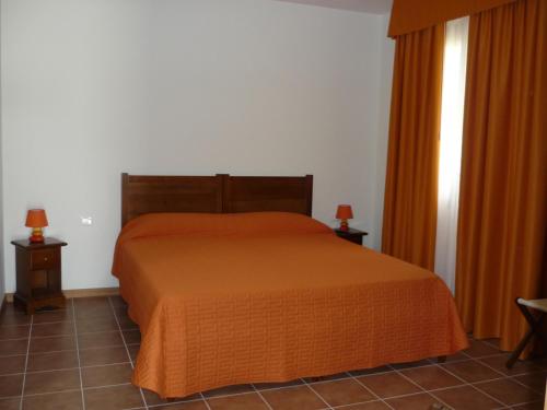 a bedroom with a bed with an orange bedspread at Agriturismo Ai Laghi in Pocenia
