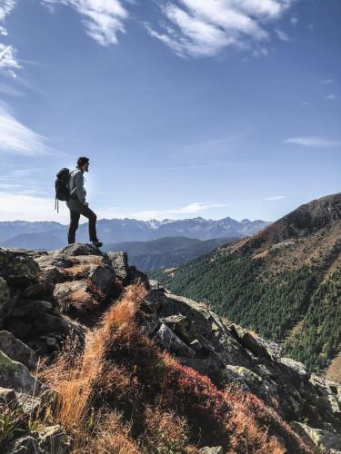 a man with a backpack standing on top of a mountain at Tratterhof Mountain Sky Hotel in Maranza