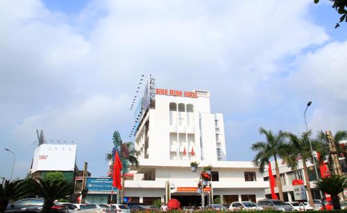 a white building with palm trees in front of it at Bình Minh Hotel in Ha Tinh
