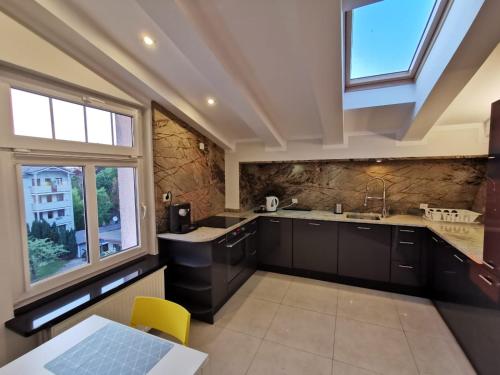 a kitchen with black cabinets and a sink and windows at Sopot Przy Plaży in Sopot