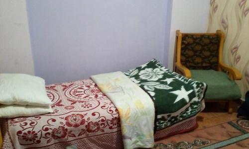 a room with a bed and a chair with pillows at Zahrate Elfirdaos Rooms للرجال فقط in Alexandria