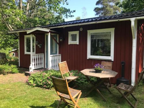 a small red house with a table and chairs in the yard at Gästhuset i Åselstad 1 in Norrköping