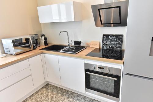 a kitchen with white cabinets and a sink and a microwave at Le 57 by Sparnapart in Épernay