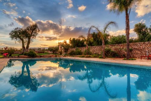 a swimming pool in a yard with a sunset at Masseria Sorani in Manduria