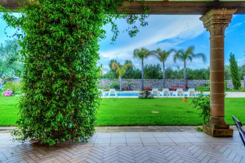 a large green hedge in a park with palm trees at Masseria Sorani in Manduria