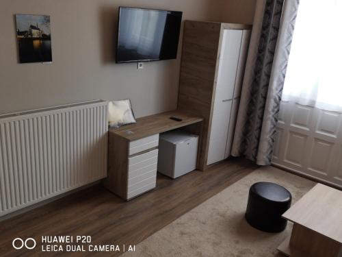 a room with a desk and a tv on a wall at Kakukk Panzió in Nyírbátor