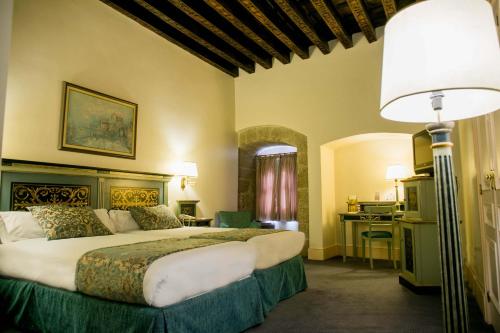 a bedroom with a large bed and a desk at Palacio de los Velada in Avila