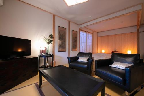 a living room with a bed and a couch and a television at Oyado Den Rikyu in Yufuin