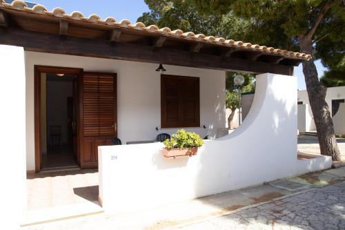 a white house with a door and a potted plant at Camping Village La Pineta in San Vito lo Capo