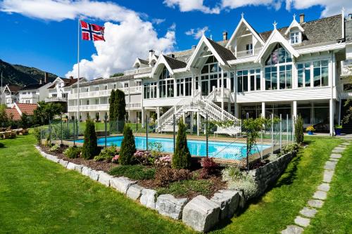 ソンダルにあるHofslund Fjord Hotelの白い大きな建物で、目の前にプールがあります。