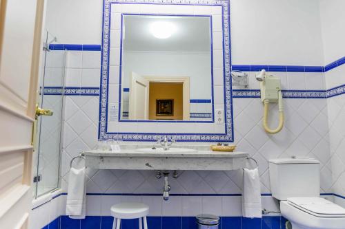 a bathroom with a sink and a mirror and a toilet at Palacio de los Velada in Avila