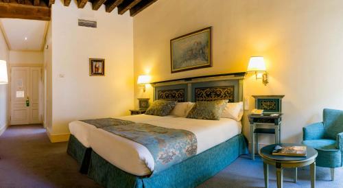 a bedroom with a large bed and a blue chair at Palacio de los Velada in Avila
