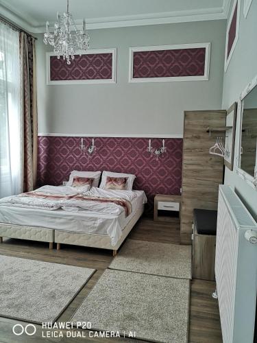 a bedroom with a bed and a purple wall at Kakukk Panzió in Nyírbátor