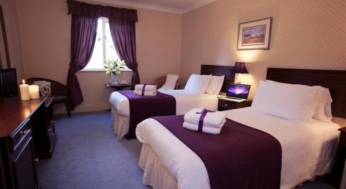 a hotel room with two beds and a laptop on a table at The Jacobean Hotel in Coventry