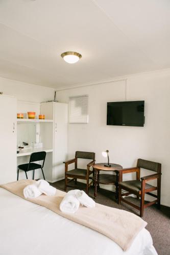 a room with two beds and a table and a tv at Pennylane Guest House in Ermelo