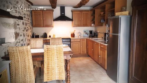 a kitchen with wooden cabinets and a stainless steel refrigerator at La Maisonnette in Entraygues-sur-Truyère