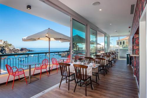 a restaurant with tables and chairs and a view of the ocean at Pestana Churchill Bay in Câmara de Lobos