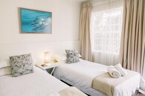 two beds in a room with a window at Pennylane Guest House in Ermelo