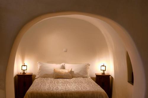 1 dormitorio con 1 cama con 2 lámparas a ambos lados en Heliophos Boutique Caves, en Oia