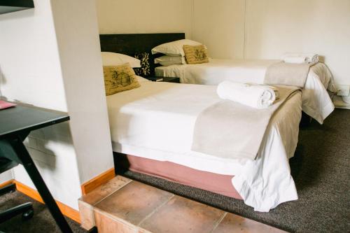 two twin beds in a room with a desk at Pennylane Guest House in Ermelo