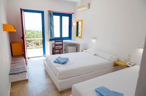 een slaapkamer met 2 bedden en een deur naar een balkon bij Plakias Bay Hotel in Plakias