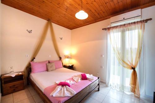 a bedroom with a bed with pink sheets and a window at Studios Katopodi in Lefkada Town