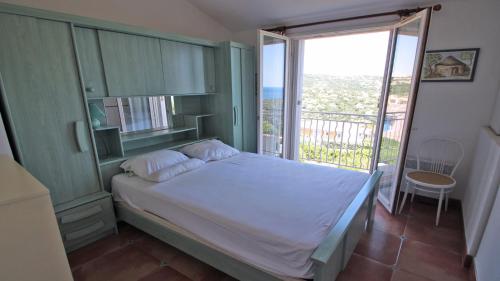 une chambre avec un lit et une grande fenêtre dans l'établissement Petit Village, aux Issambres