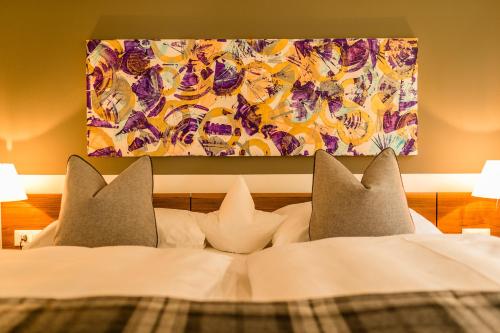 una cama con almohadas y una pintura en la pared en Hidalgo Suites, en Merano