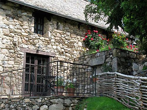 a stone building with a balcony with flowers on it at La Maisonnette in Entraygues-sur-Truyère