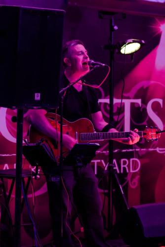 a man sitting on a stage with a guitar at Scott's Hotel in Killarney