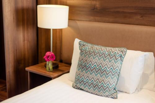 a bed with a pillow and a table with a lamp at Scott's Hotel in Killarney