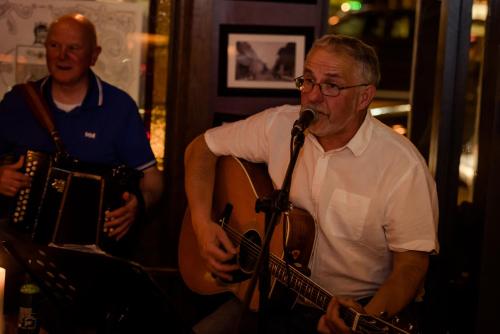 two men playing instruments with a microphone and a guitar at Scott's Hotel in Killarney