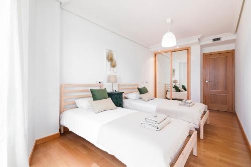 Duas camas num quarto com paredes brancas e pisos de madeira em Lanzarote Siglo XXI Sea View em Arrecife