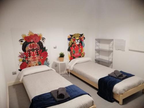 three beds in a room with paintings on the wall at Dos Torres Puerta del Carmen - Moderno y Espacioso en el Centro in Zaragoza