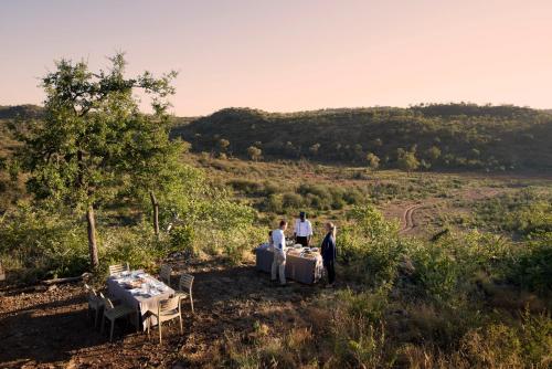 a group of people standing around tables in a field at Madikwe Safari Lodge in Madikwe Game Reserve