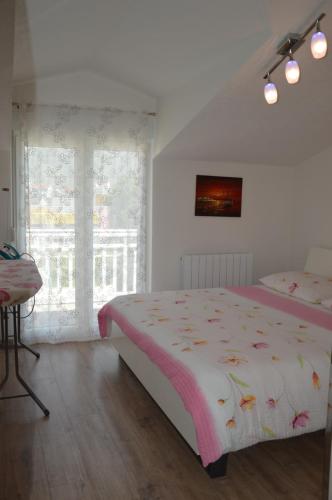 a white bedroom with a bed and a window at Apartments Babic in Podstrana