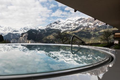 een zwembad met uitzicht op een met sneeuw bedekte berg bij Hotel Maya Caprice in Wengen