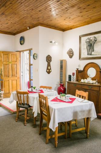 a dining room with two tables with white tablecloths at Pennylane Guest House in Ermelo