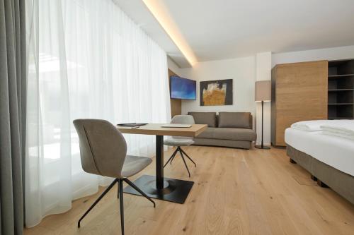 a bedroom with a desk and a bed and a couch at Hotel Gösser Bräu in Wels