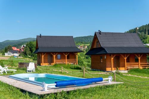 a swimming pool in front of a log cabin at Chatki Niwki u Zbója in Krościenko