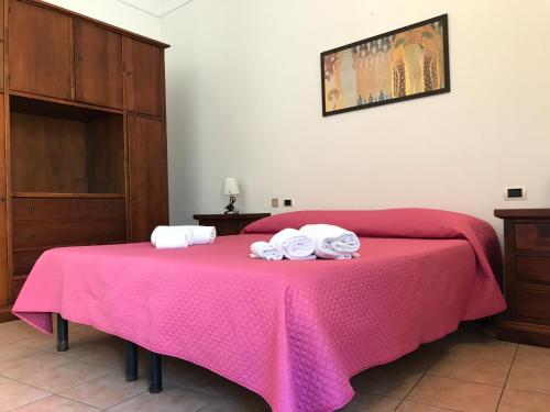 a bedroom with a pink bed with towels on it at Life Hotels Residence dei Baroni in Siracusa