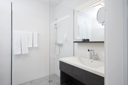 a white bathroom with a sink and a shower at Hotel Gösser Bräu in Wels