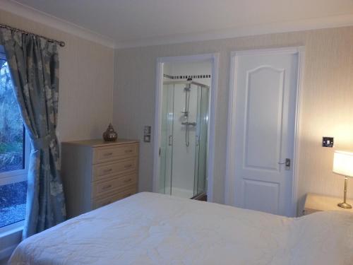 a bedroom with a bed and a glass shower at Grand eagles Riverside Extra large lodge in Auchterarder